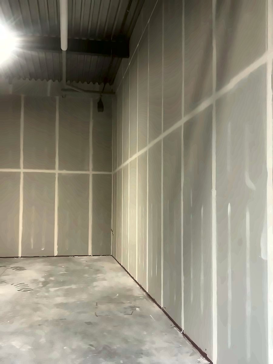 An empty unit with drywall boarded and taped to full height and a bare concrete floor