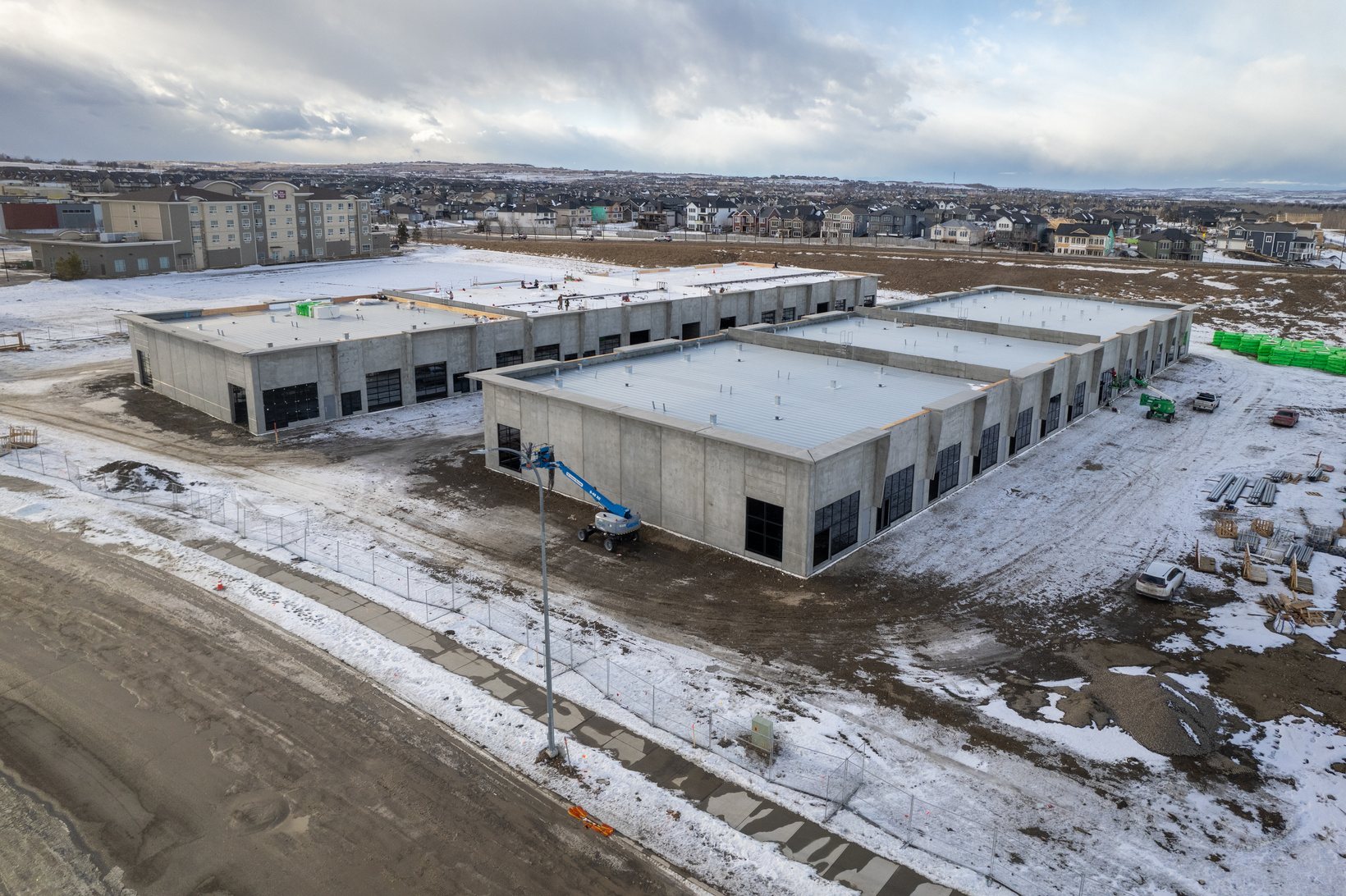 Precast concrete walls of both Foundry buildings standing on a snowy site, with a boom lift at work