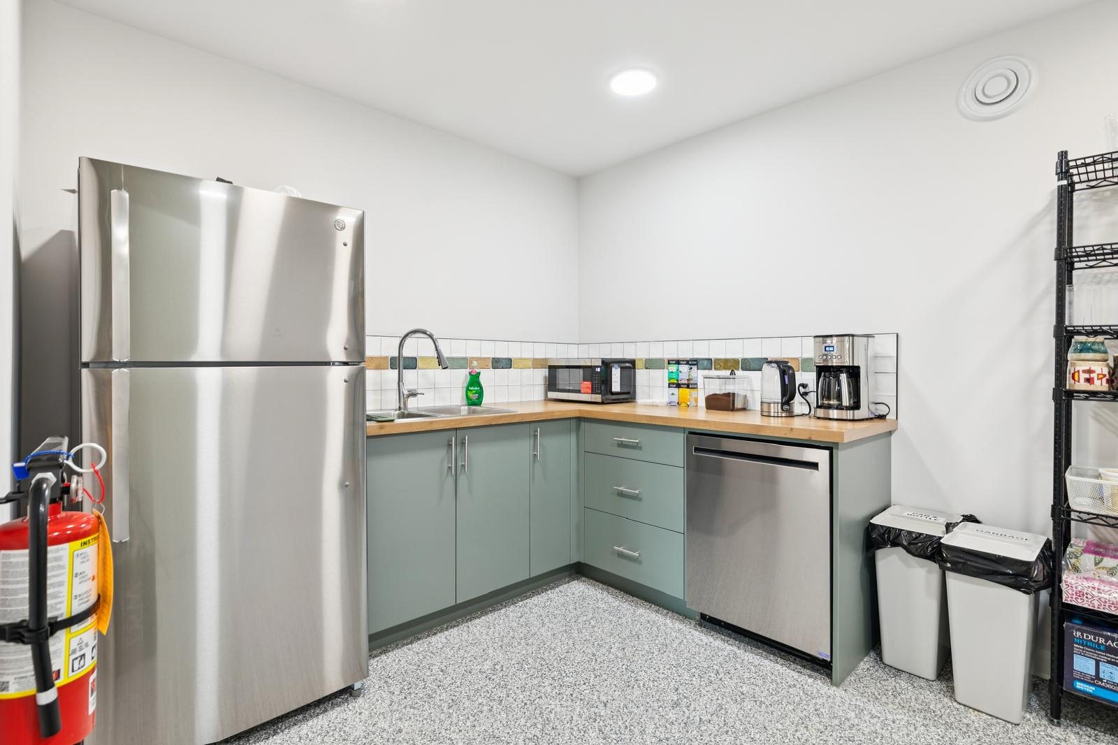 A bright kitchen with sage cabinets, a butcher-block counter, a fridge and a dishwasher